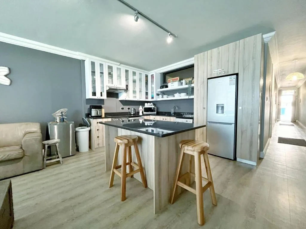 Modern kitchen with black countertop, white cabinetry, and wooden bar stools