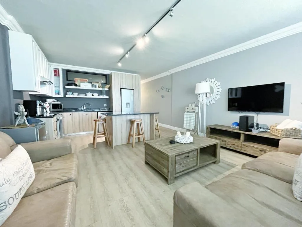 Modern open-plan lounge with comfortable seating and flat-screen television mounted on wall