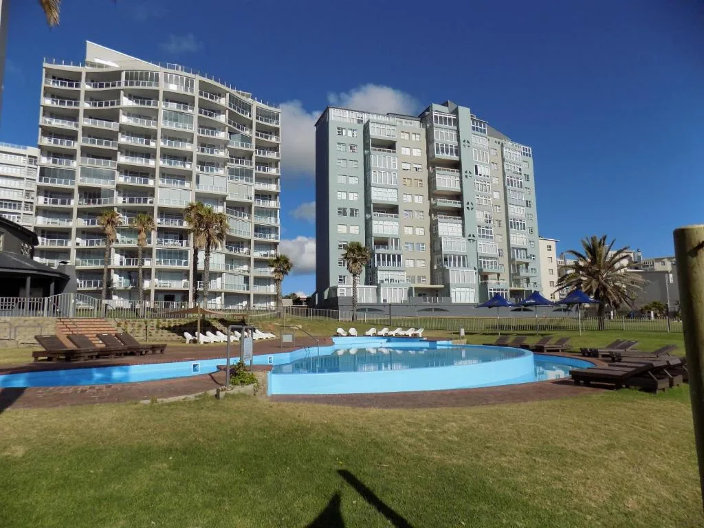 Swimming pool with loungers and apartment buildings in background