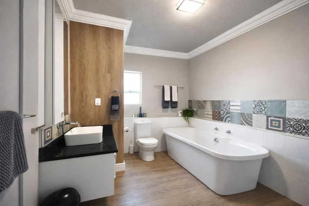 Modern bathroom with freestanding tub, double vanity, and patterned tile accents