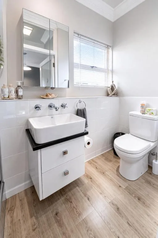 Modern bright bathroom with vessel sink, mirrored cabinet, and toilet