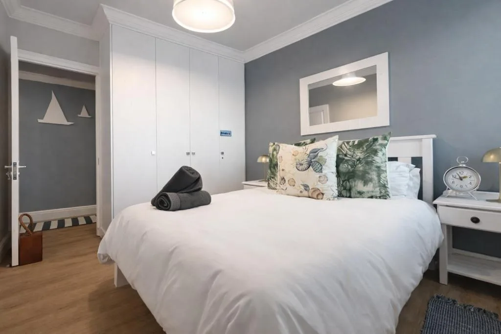 Modern bedroom with white bed, decorative pillows, and gray accent walls