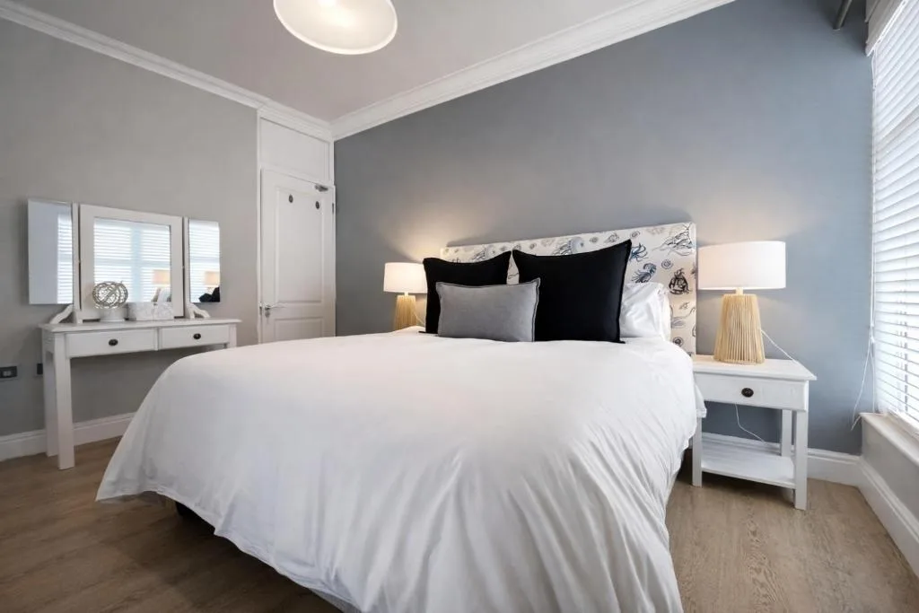 Bright modern bedroom with queen bed, white linens, black pillows, and elegant furnishings