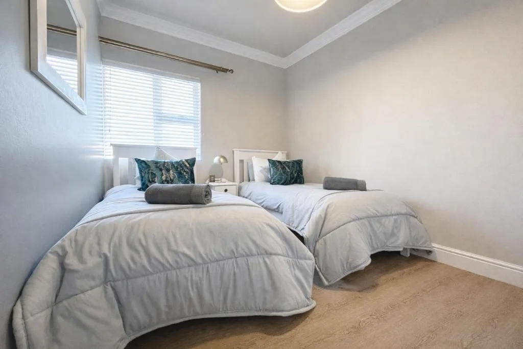 Bright twin bedroom with white bedding and green accent pillows