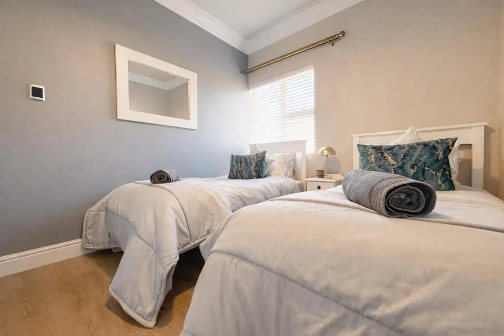Bright bedroom with two single beds, white bedding, and decorative pillows