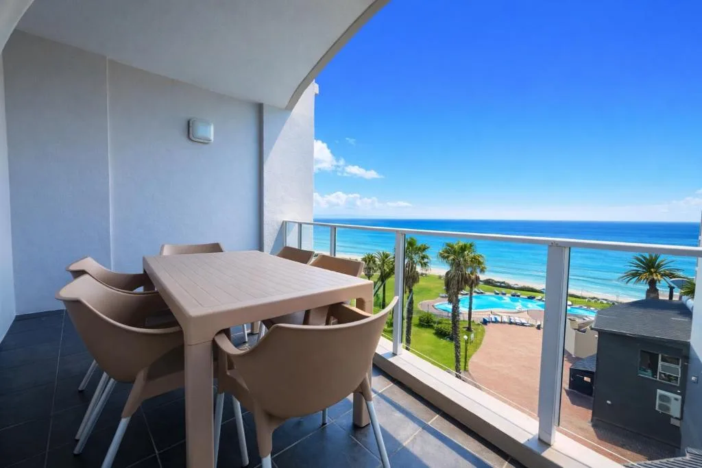 Balcony with dining table overlooking ocean, beach, and palm trees