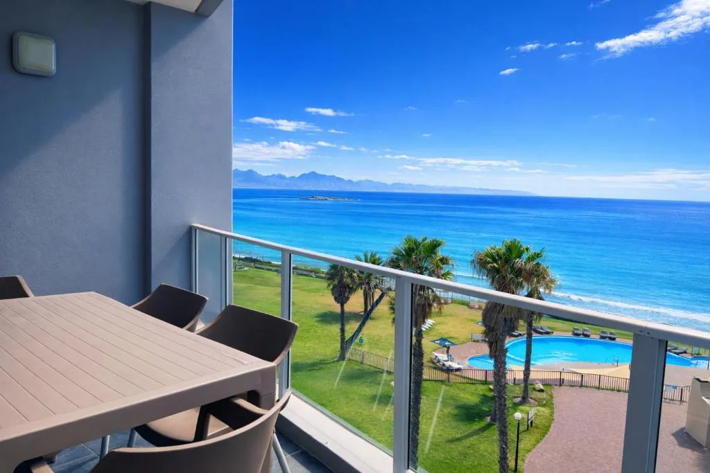 Oceanfront balcony with dining table overlooking beach and mountains