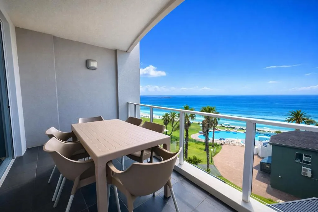 Balcony with dining table overlooking pristine blue ocean and beach