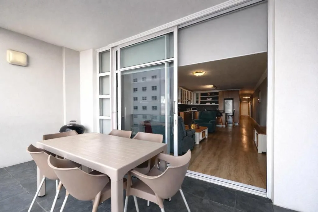 Modern dining table with four upholstered chairs overlooking open-plan lounge