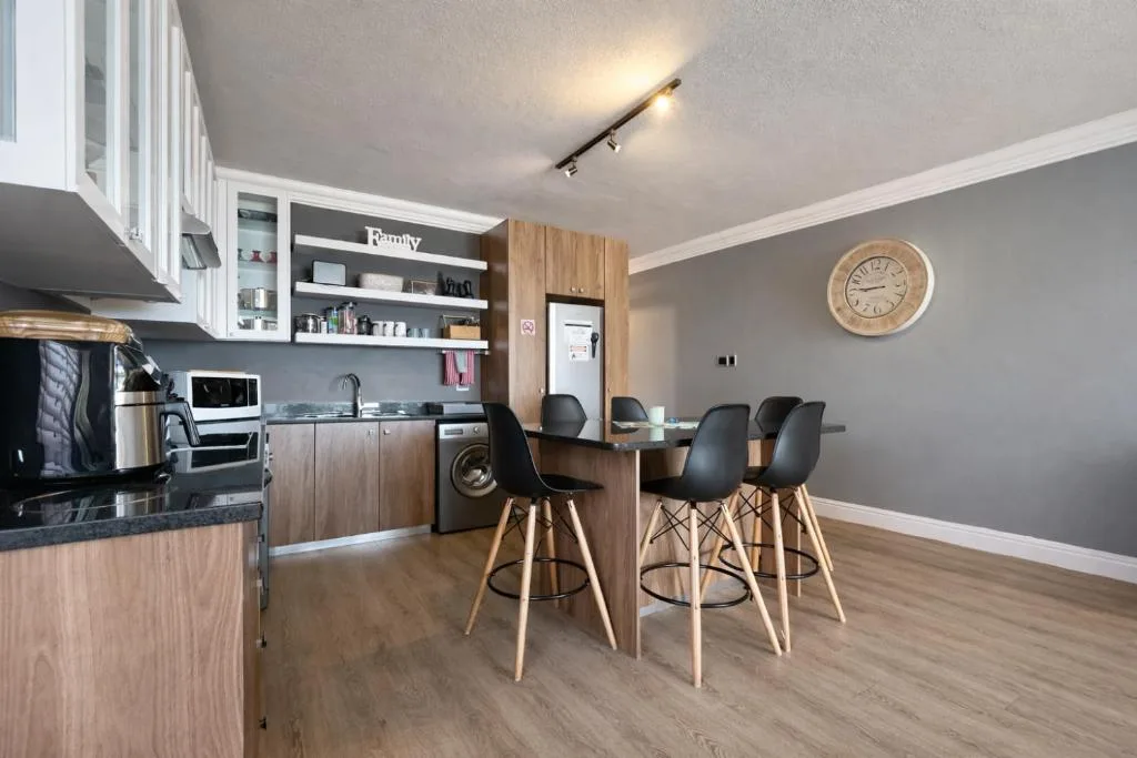 Modern kitchen with wooden cabinetry, black countertop, and bar seating area