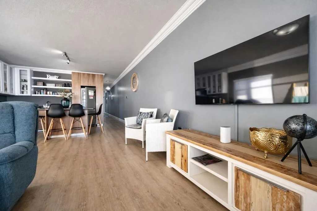 Modern open-plan lounge with blue sofa, TV, and contemporary furnishings