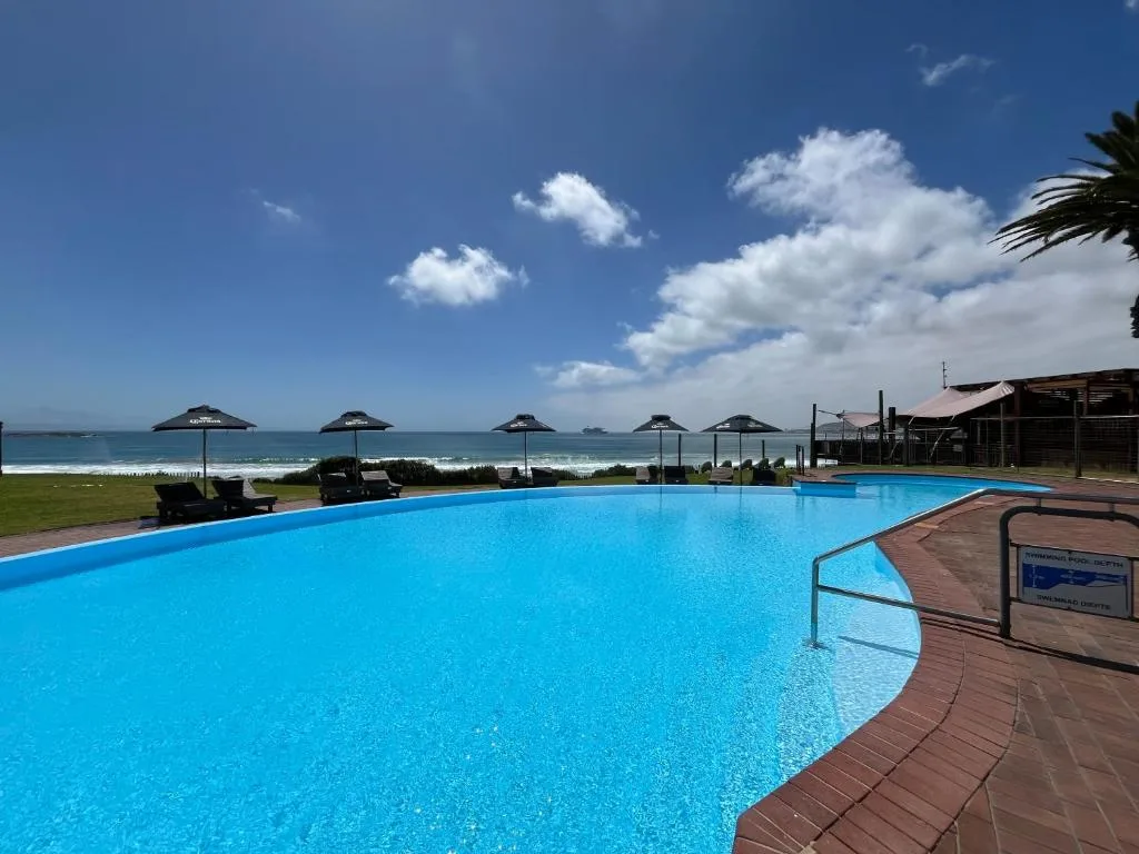 Beachfront swimming pool with ocean and sandy beach view beyond