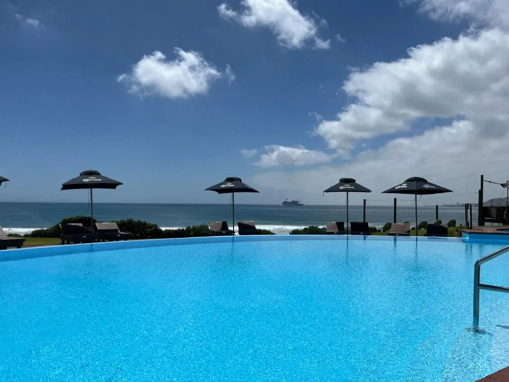 Expansive poolside with ocean views, umbrellas, and coastal scenery beyond