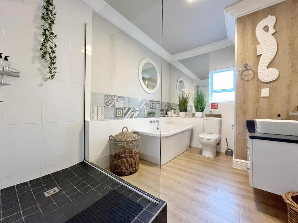 Modern bathroom with walk-in shower, vanity, toilet, and coastal decor accents