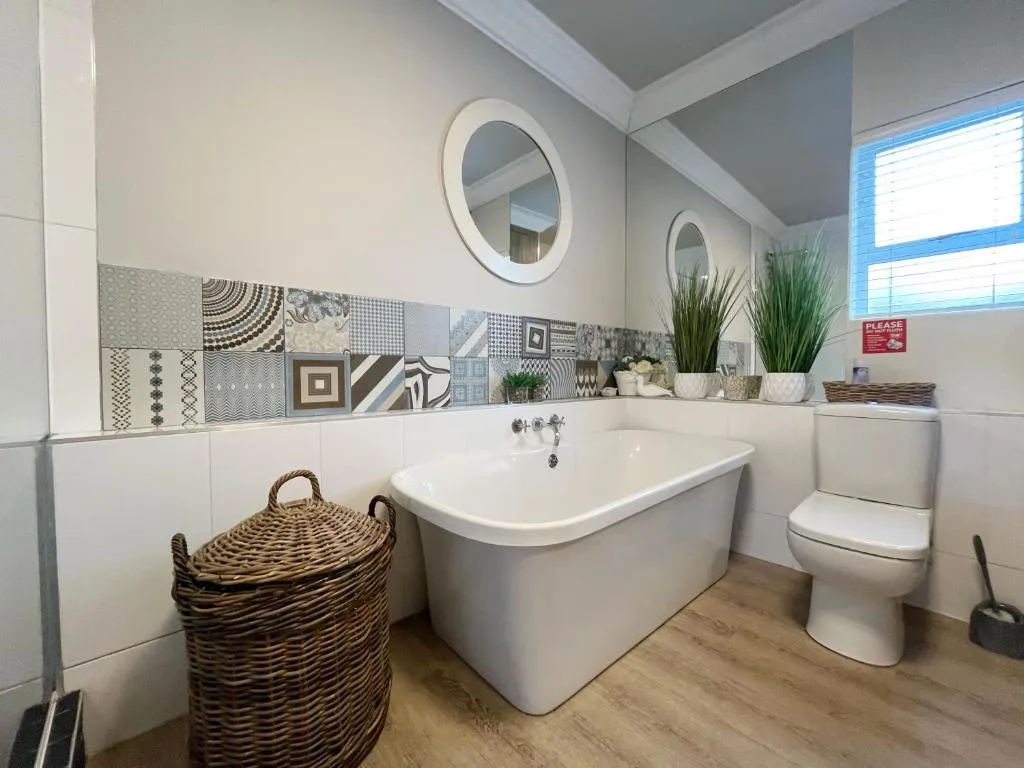 Modern bathroom with freestanding tub, toilet, and decorative tile backsplash