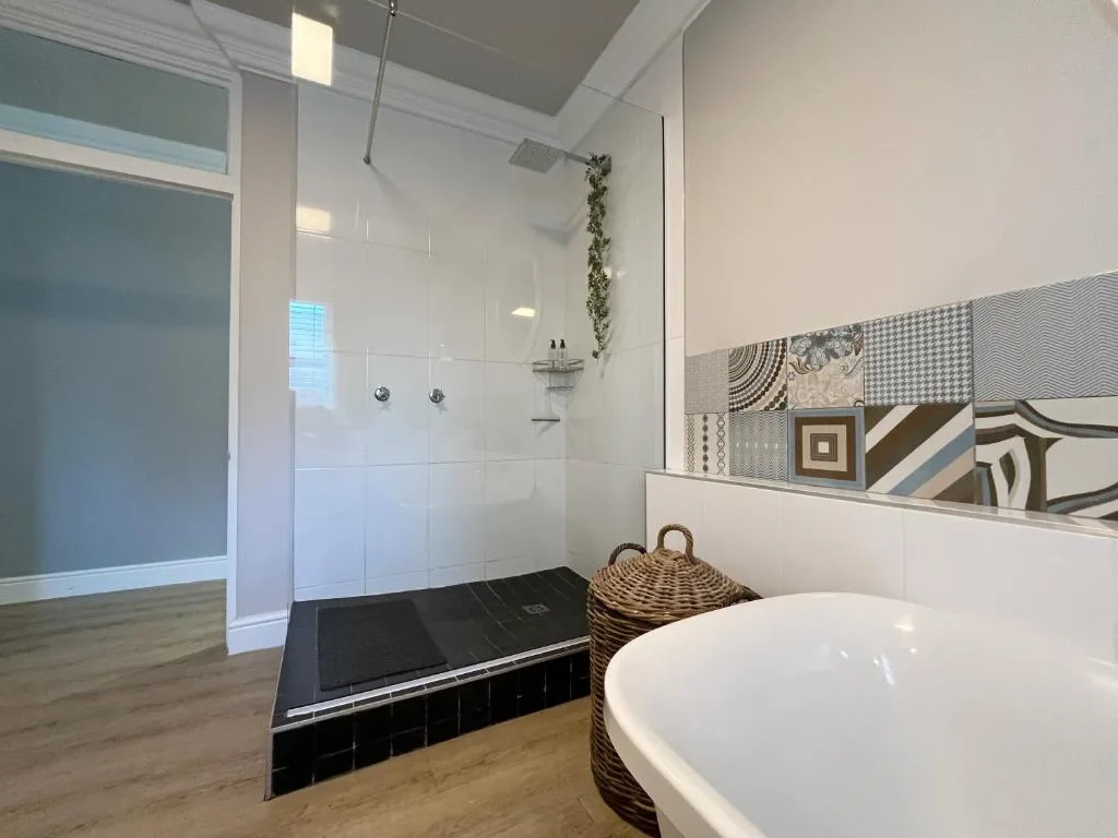 Modern bathroom with walk-in shower, freestanding bathtub, and decorative tile accents
