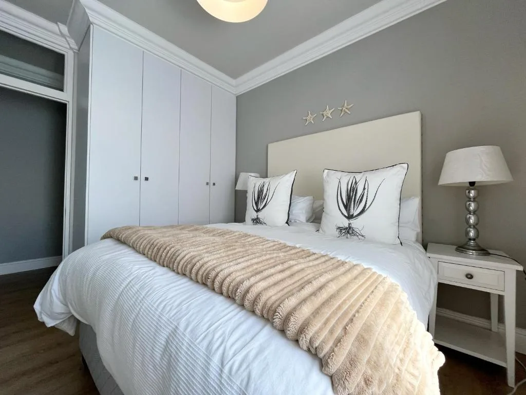 Modern bedroom with queen bed, cream headboard, white wardrobe, and bedside lamp