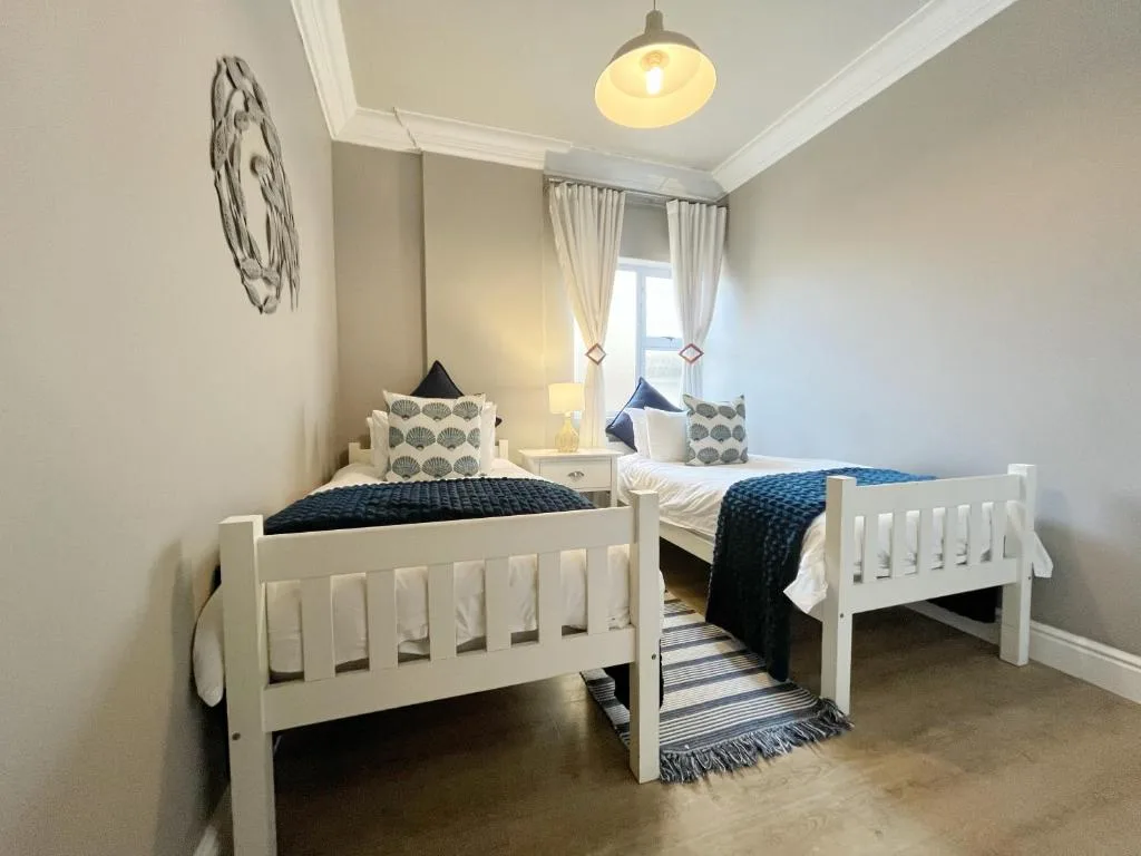 Twin bedroom with white beds, navy bedding, and nautical decor accents