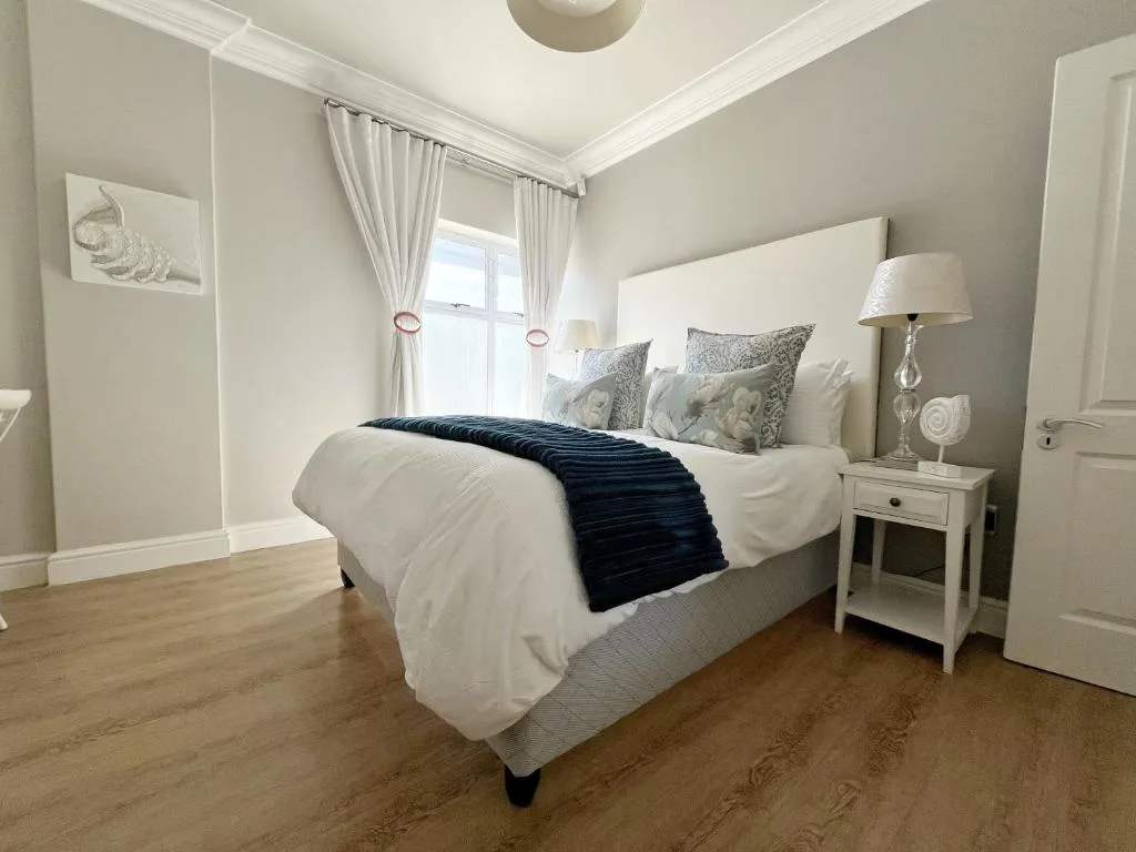 Bright bedroom with queen bed, neutral bedding, and coastal decor accents