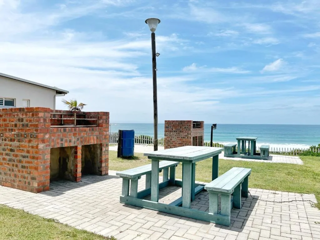 Beachfront picnic area with green wooden tables and ocean view