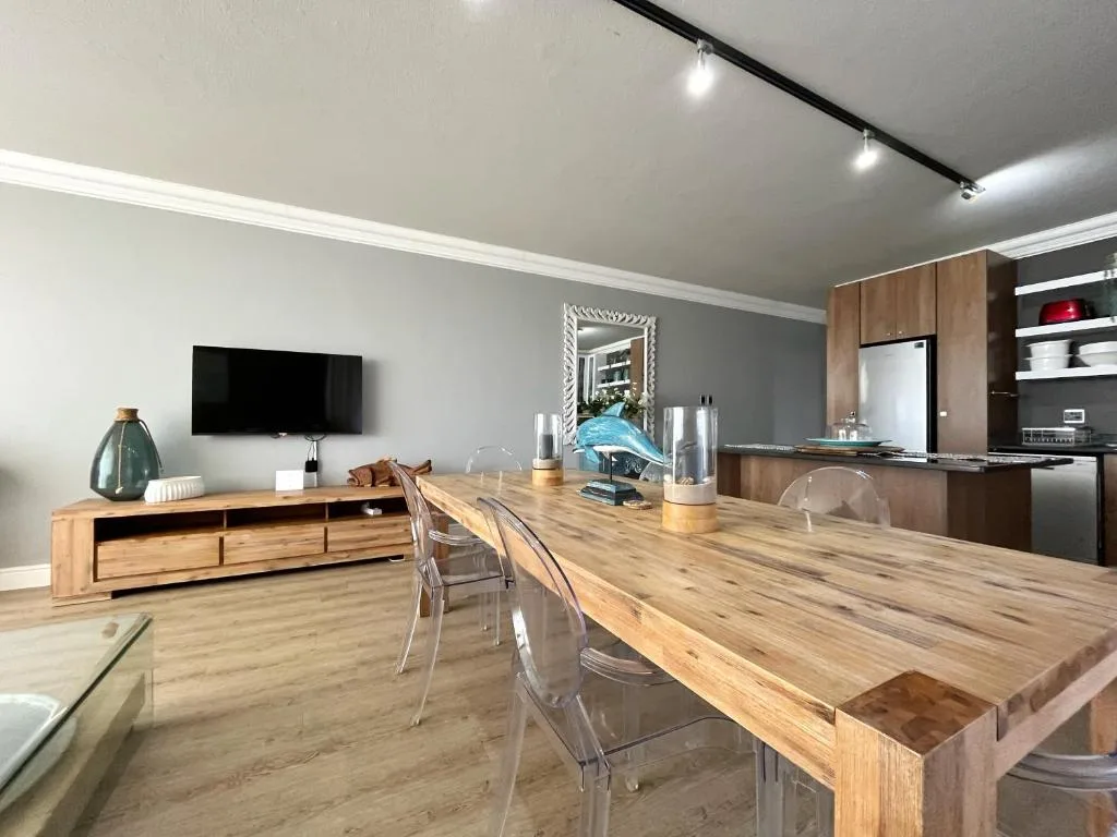 Open-plan dining and living area with wooden table and modern kitchen
