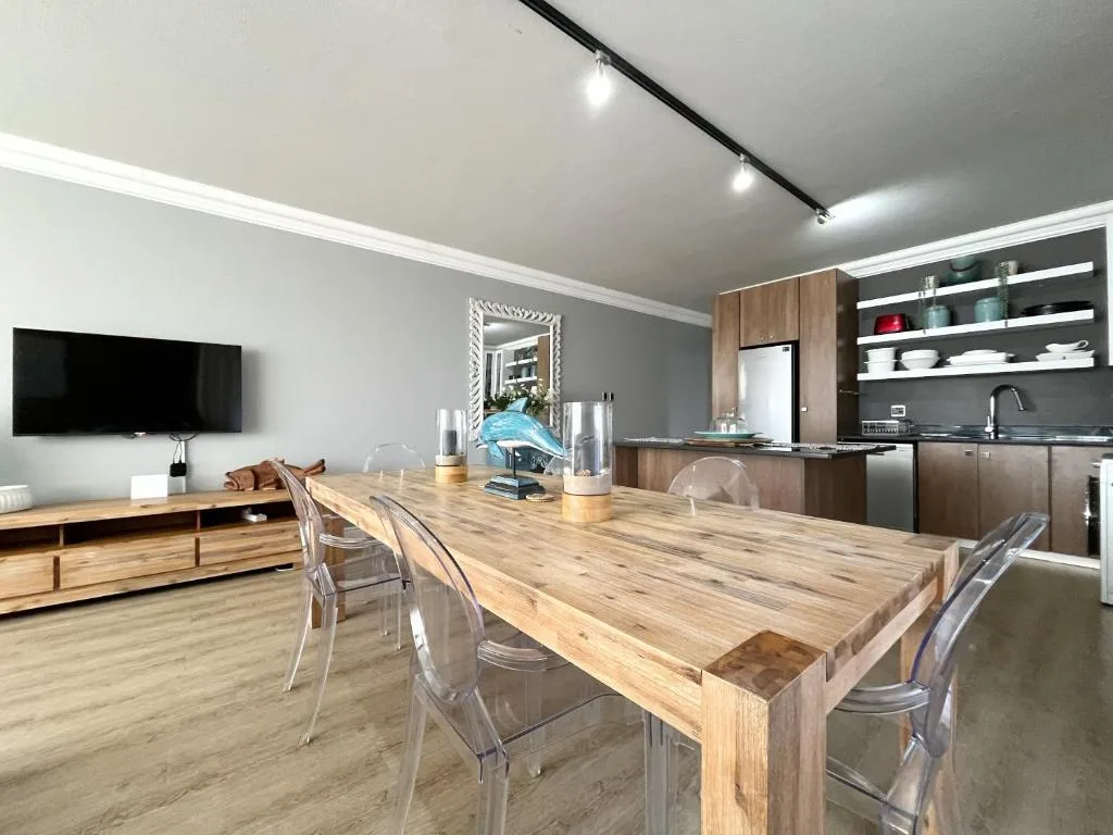Open-plan dining area with wooden table and modern kitchen cabinetry visible