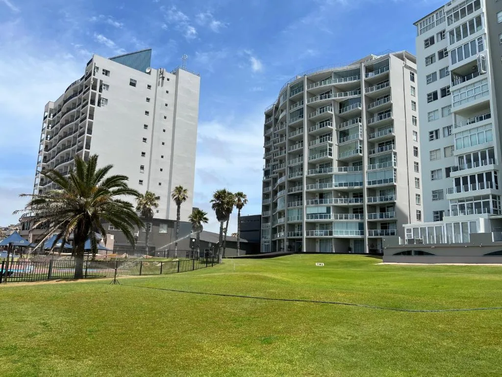 Modern apartment buildings with manicured lawn and palm trees, coastal setting