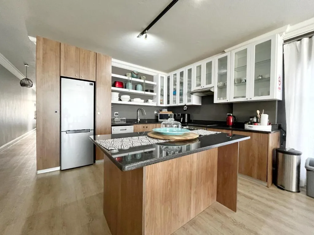 Modern kitchen with wooden cabinetry, dark countertops, island bench, and stainless steel appliances