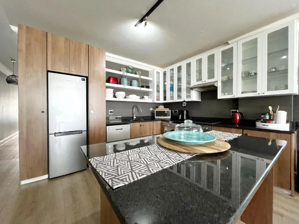 Modern kitchen with black countertops, wood cabinetry, and white glass-fronted cupboards