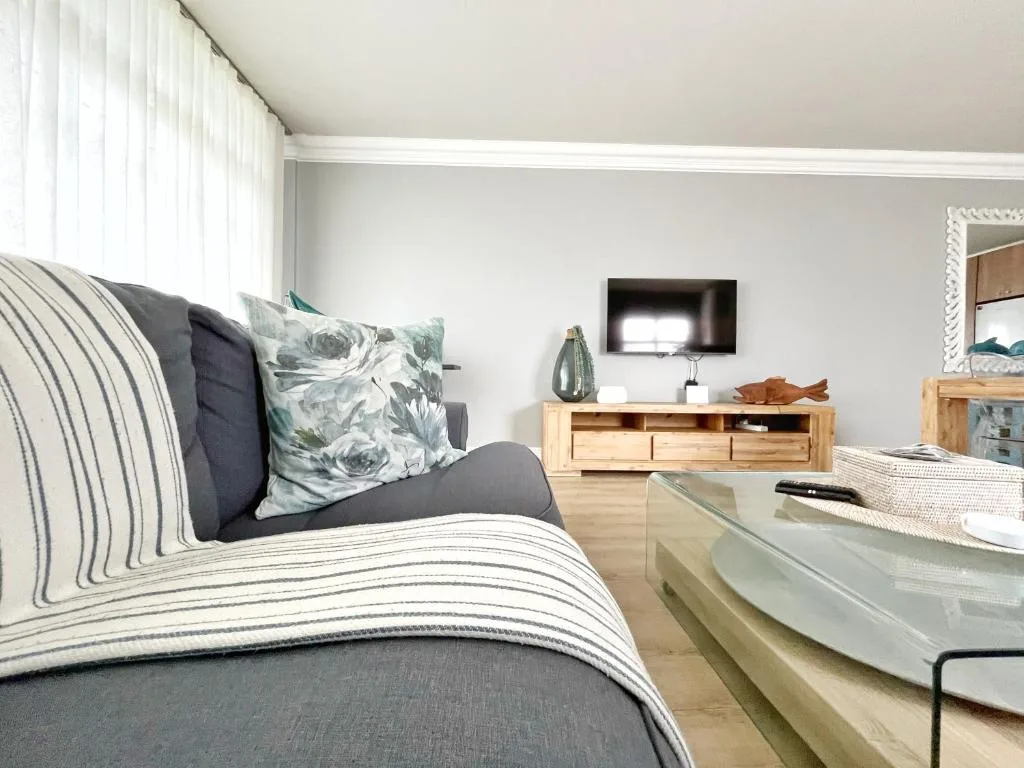 Modern lounge with striped sofa, floral pillows, and wall-mounted television