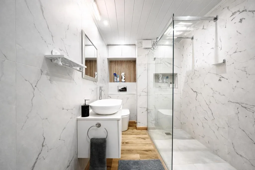 Modern bathroom with marble-effect tiles, vessel sink, and walk-in shower enclosure