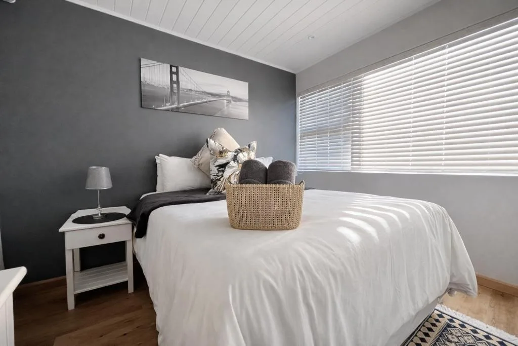 Bright bedroom with white bed, gray accent wall, and modern decor