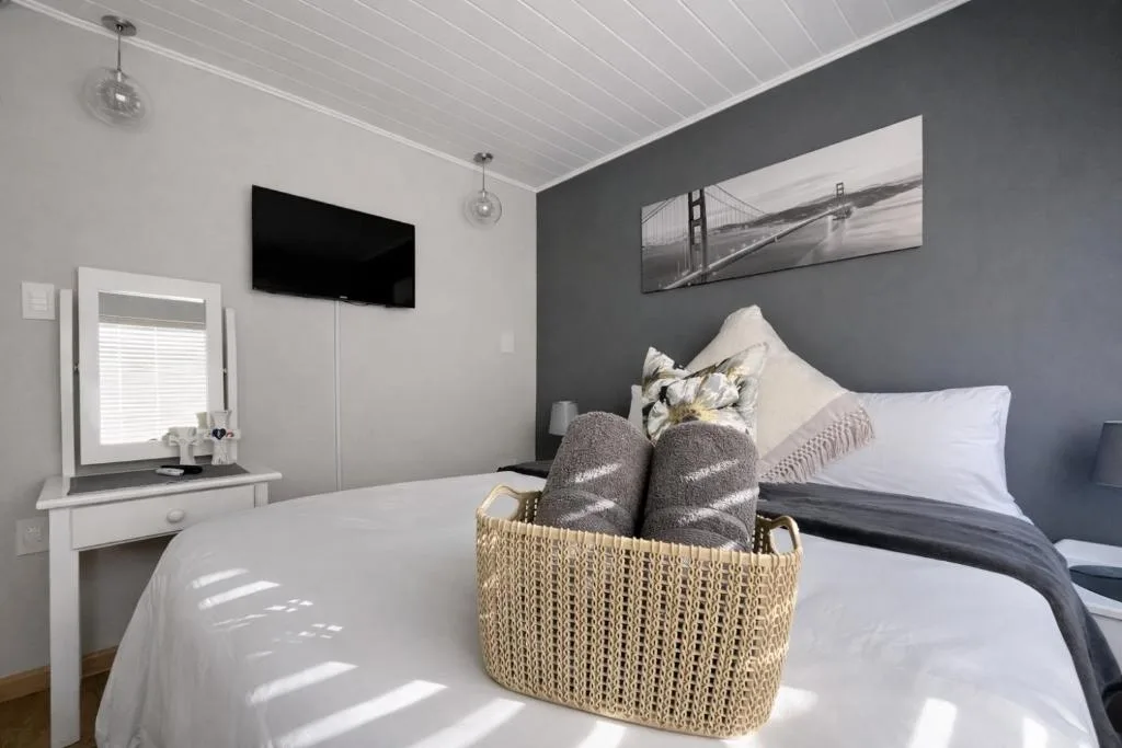 Modern bedroom with queen bed, vanity, TV, and contemporary decor