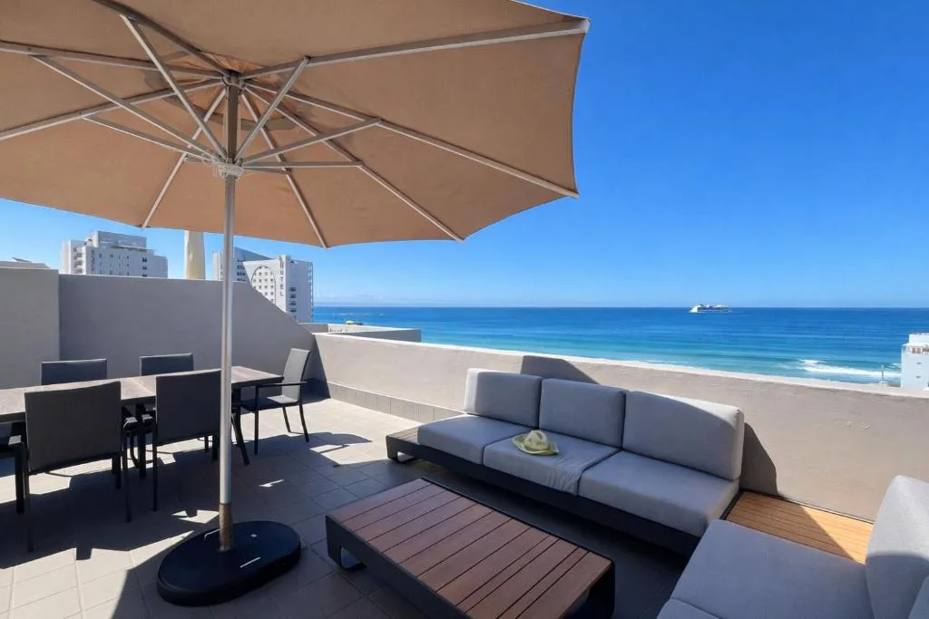 Spacious oceanfront deck with lounge seating, dining table, and beach view