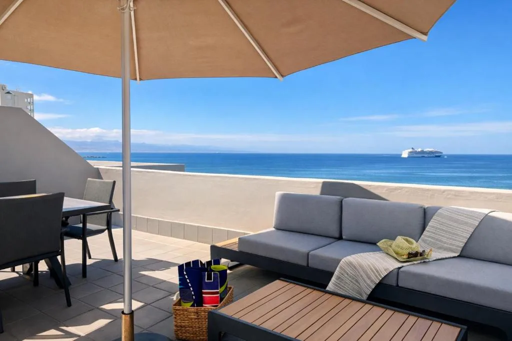 Beachfront deck with lounge seating, umbrella, and ocean views