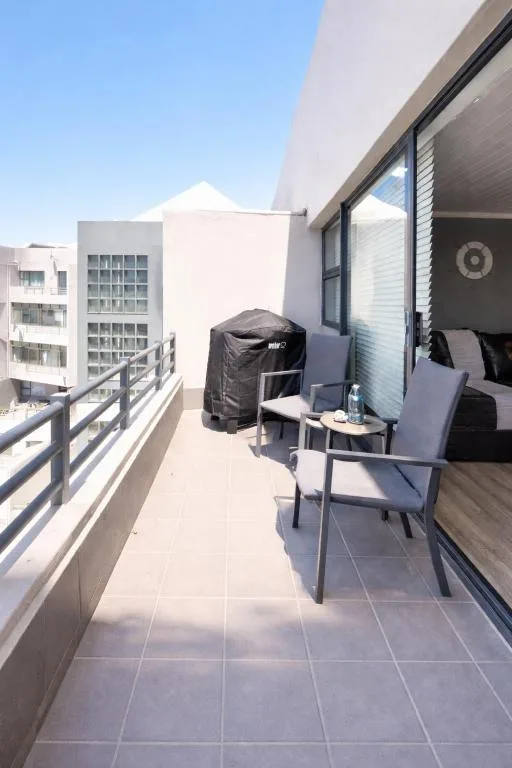 Modern apartment balcony with outdoor seating and braai grill overlooking town
