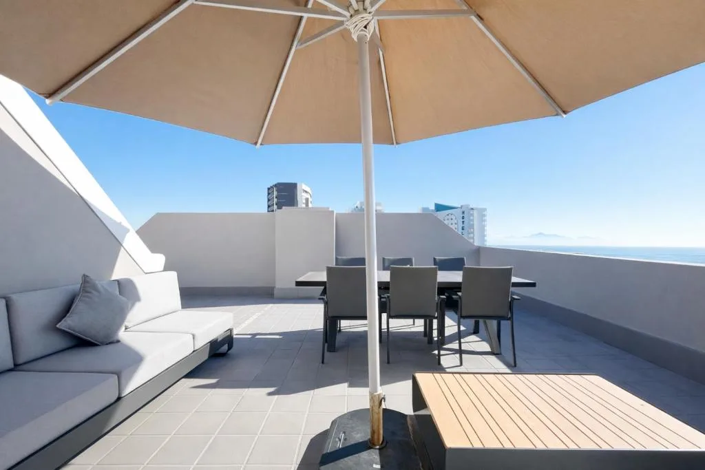 Rooftop terrace with umbrella, seating, ocean view horizon beyond