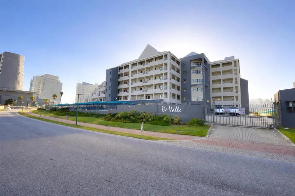 Modern multi-story apartment building with gated entrance and manicured grounds