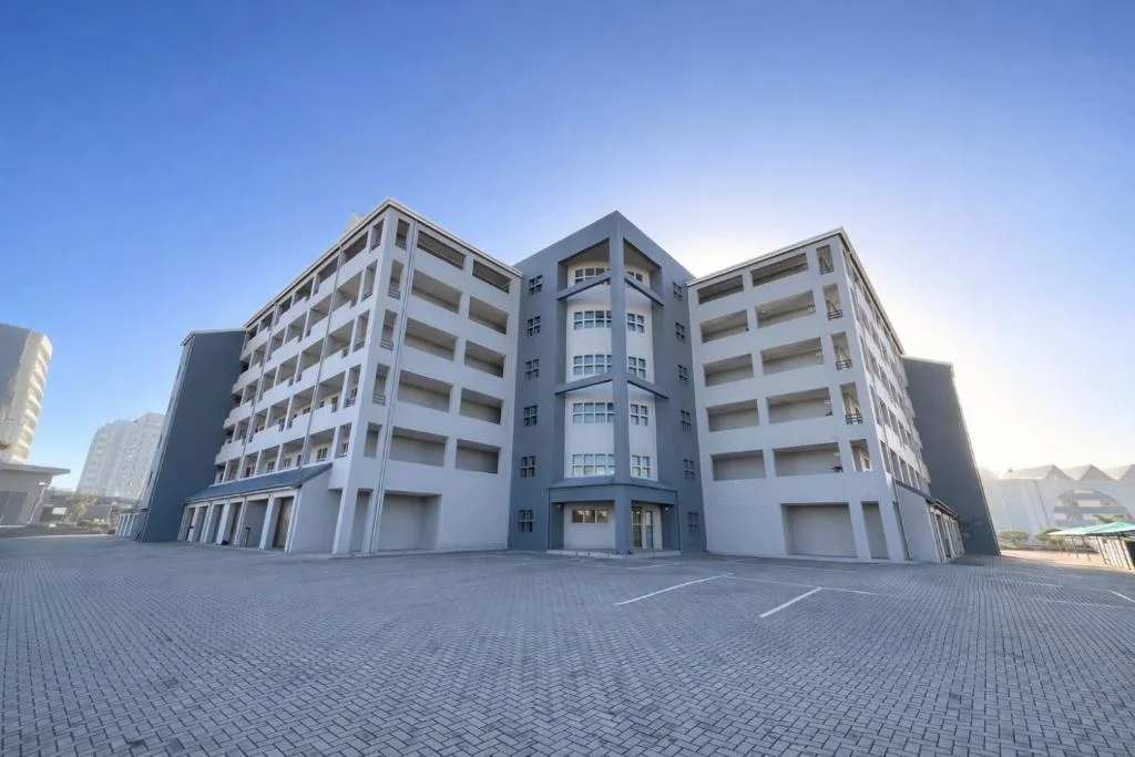 Modern multi-story apartment building with white and blue facade and parking area