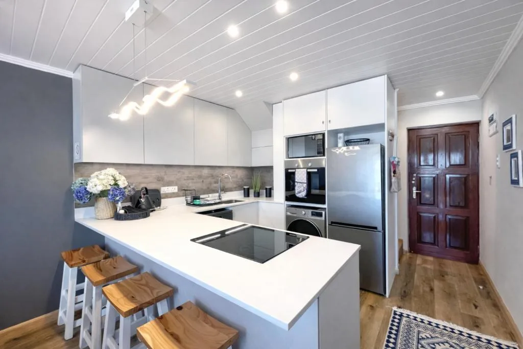 Modern kitchen with white cabinetry, island seating, and stainless steel appliances