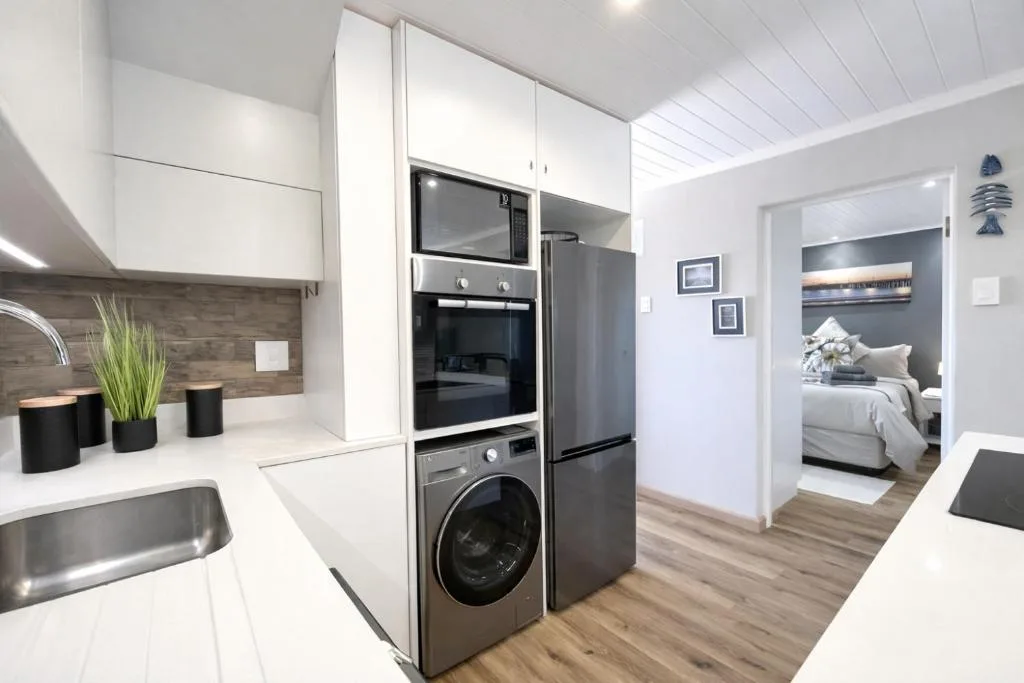Modern kitchen with white cabinetry, stainless steel appliances, and wood backsplash