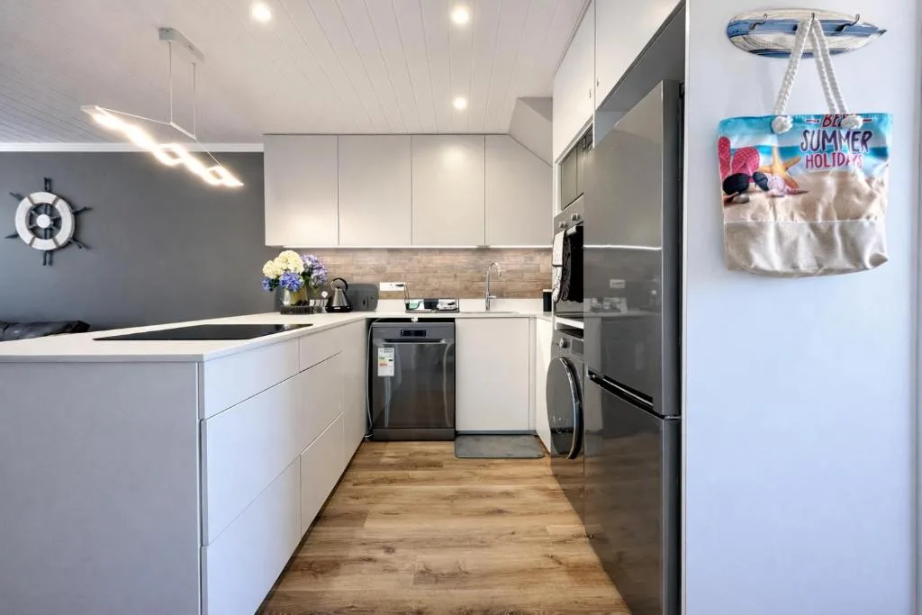 Modern kitchen with white cabinetry, stainless steel appliances, and wooden flooring