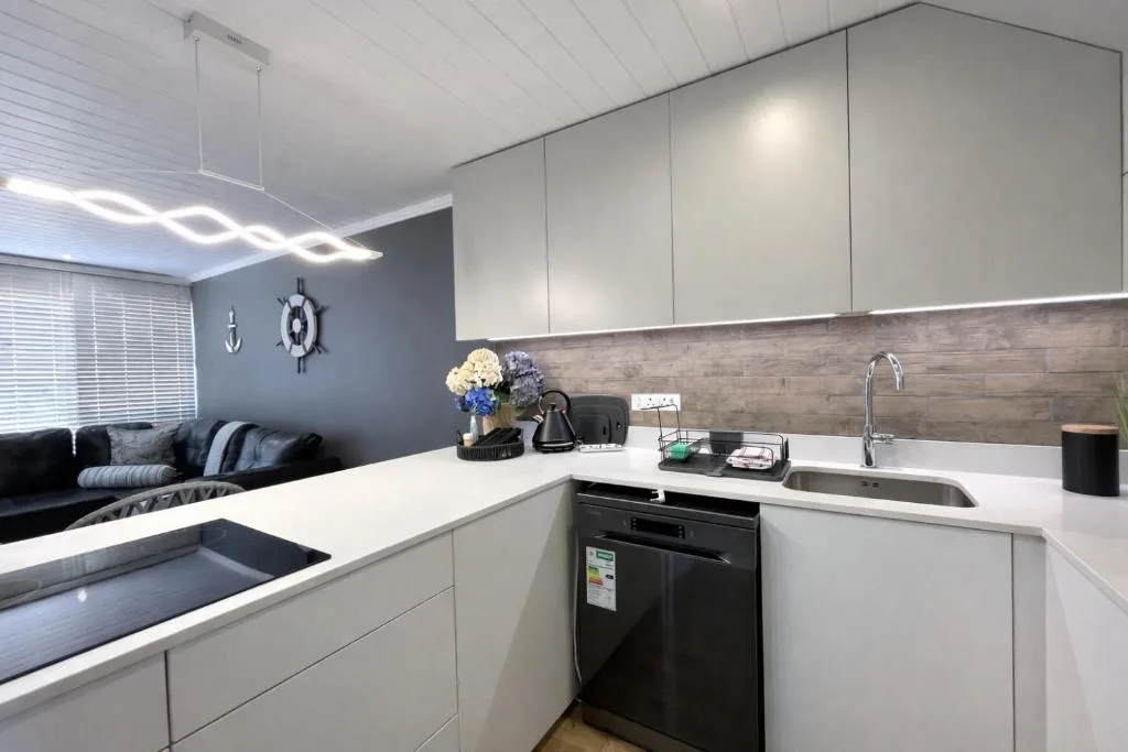 Modern white kitchen with stainless steel sink and black appliances