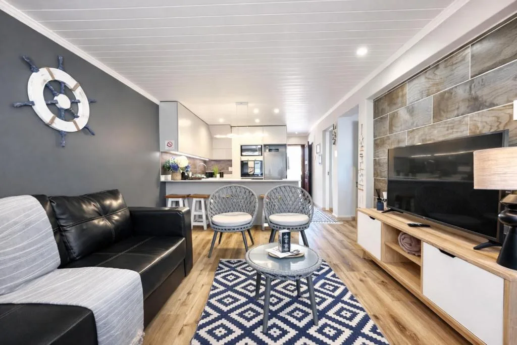 Modern lounge with black leather sofa, TV unit, and nautical decor elements