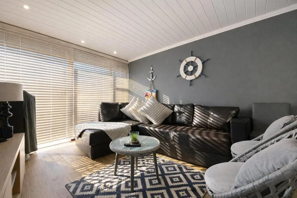 Modern lounge with black leather sofa, nautical decor, and bright windows