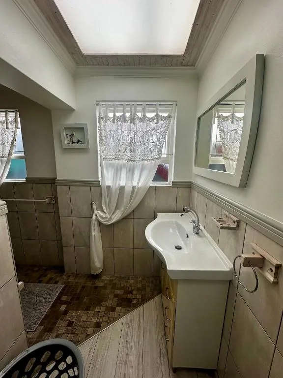 Bathroom with white basin sink, mirror, and shower curtain by window