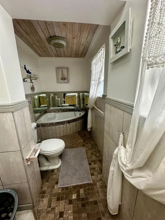 Charming bathroom with clawfoot tub, toilet, and wooden ceiling detail
