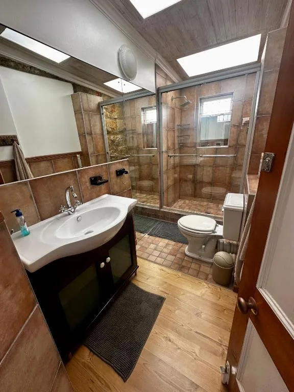 Modern bathroom with curved vanity sink, walk-in shower, and toilet