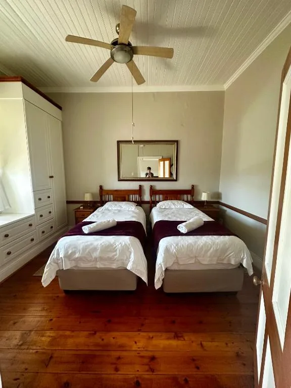 Twin beds with white linens in bright bedroom with wooden floors