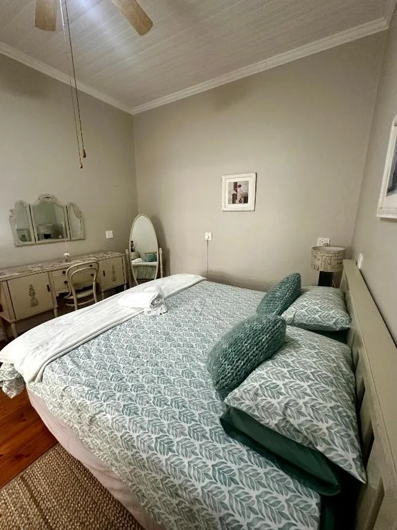 Cozy bedroom with double bed, green patterned pillows, wooden floors